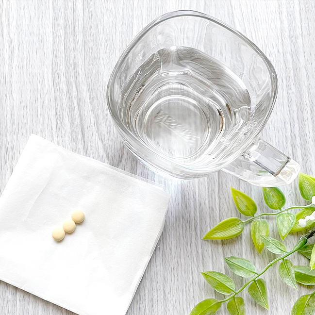 薬がそばにある白湯を入れたコップ
